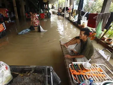 Seorang pria duduk di ranjang bambu saat banjir menyusul hujan di pinggiran Phnom Penh, Kamboja (14 /10/2020). Pejabat bencana Kamboja mengatakan Rabu bahwa lebih dari 10.000 orang telah dievakuasi ke tempat aman setelah badai tropis melanda yang menyebabkan banjir bandang.  (AP Photo/Heng Sinith)