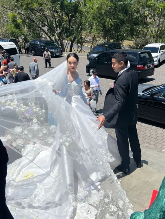 Baru menikah di Bali, Pamela Bowie tampil menawan dengan bawl gaun putih lengan panjang satin lengkap dengan veil berbordir dari Monica Ivena. [@pammybowie]