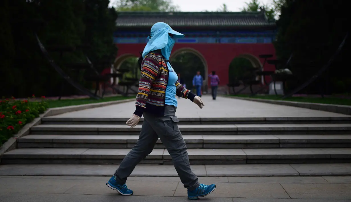 Seorang wanita mengenakan topi berjalan di taman di Beijing (19/4). Beijing memiliki populasi 21.150.000 pada tahun 2013. (AFP Photo/Wang Zhao)