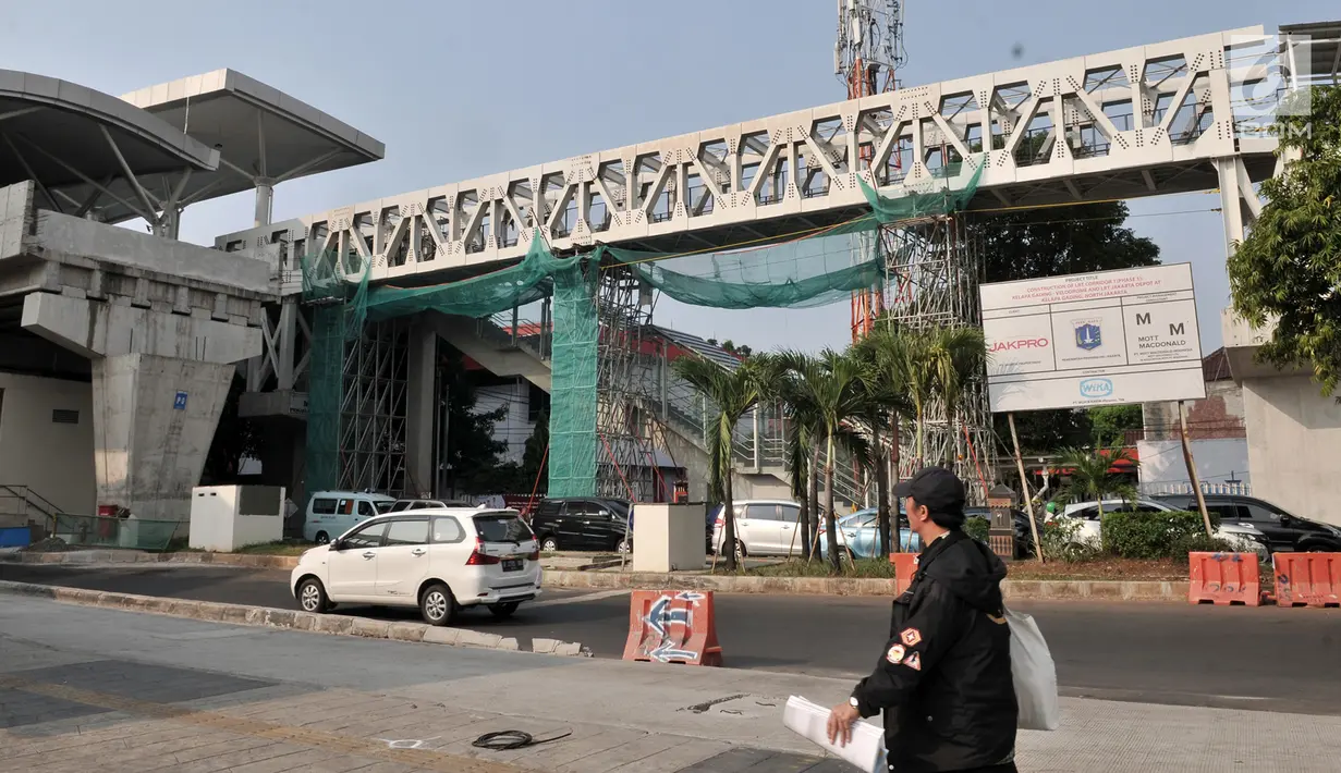 Pejalan kaki melintas dekat Skybridge Stasiun LRT Velodrome-Halte Transjakarta Pemuda, Rawamangun, Jakarta, Selasa (11/6/2019). Pengoperasian LRT Kelapa Gading-Velodrome kembali diundur karena belum selesainya pembangunan Skybridge LRT Velodrome-Halte Transjakarta Pemuda. (merdeka.com/Iqbal Nugroho)