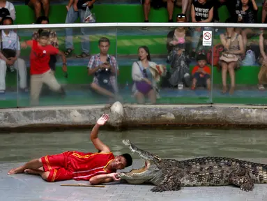 Seorang pria beratraksi dengan meletakkan kepalanya kedalam mulut buaya di Sriracha Tiger Zoo, Provinsi Chonburi , Thailand , 7 Juni 2016. Aksi nekat ini mengundang decak kagum wisatawan yang hadir. (REUTERS / Chaiwat Subprasom)