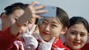 Sejumlah wanita berswafoto di sela penyambutan para peserta Kongres Rakyat Nasional di Beijing, China, Senin (4/3). Para wanita berparas cantik tersebut bertugas menyambut para tamu yang menghadiri kongres. (AP Photo/Andy Wong)