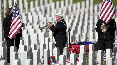 Pensiunan Angkatan Laut Amerika Serikat Yeoman Mark Stallins memainkan Taps untuk keluarga prajurit yang gugur di sebuah kuburan di Pemakaman Nasional Fort Logan, Sheridan, Colorado, Amerika Serikat, 30 Mei 2022. (AP Photo/David Zalubowski)