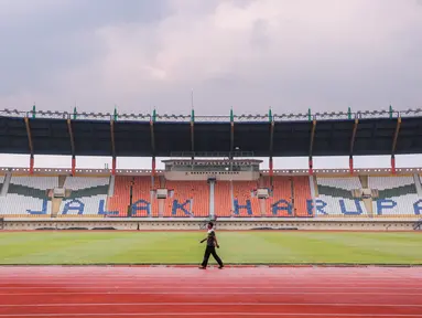 Seorang pekerja terlihat berjalan di Stadion Si Jalak Harupat, Kecamatan Kutawaringin, Kecamatan Bandung, Jawa Barat yang tengah dipersiapkan untuk salah satu venue Piala Dunia U-17 2023 pada Sabtu (21/10/2023). Stadion SJH akan menjadi kandang untuk Grup D, Grup F, dan dua laga babak 16 besar. (Bola.com/Bagaskara Lazuardi)