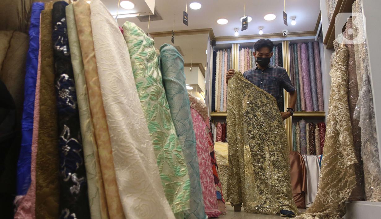 Pekerja menyusun bahan kain di Pasar Tanah Abang, Jakarta, Sabtu (27/11/2021). Utilisasi industri tekstil dan produk tekstil dalam negeri menunjukkan kinerja yang positif menjelang akhir 2021. Utilisasi industri itu berada di posisi 80 - 85 persen pada awal kuartal IV/2021. (Liputan6.com/Angga Yunia