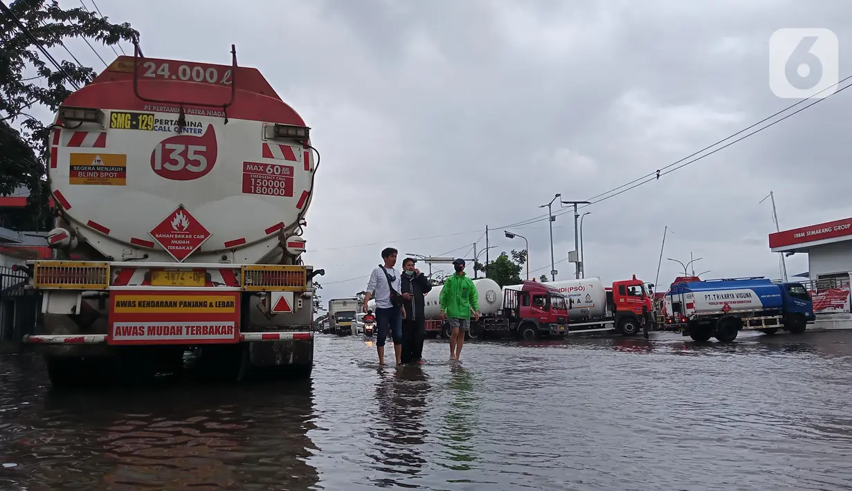 Warga menerobos banjir yang menggenangi daerah Kaligawe, Kota Semarang, Selasa (9/2/2021). Banjir dengan ketinggian 30 hingga 90 cm ini melumpuhkan akses Semarang ke Demak dan sebaliknya. (Liputan6.com/Gholib)