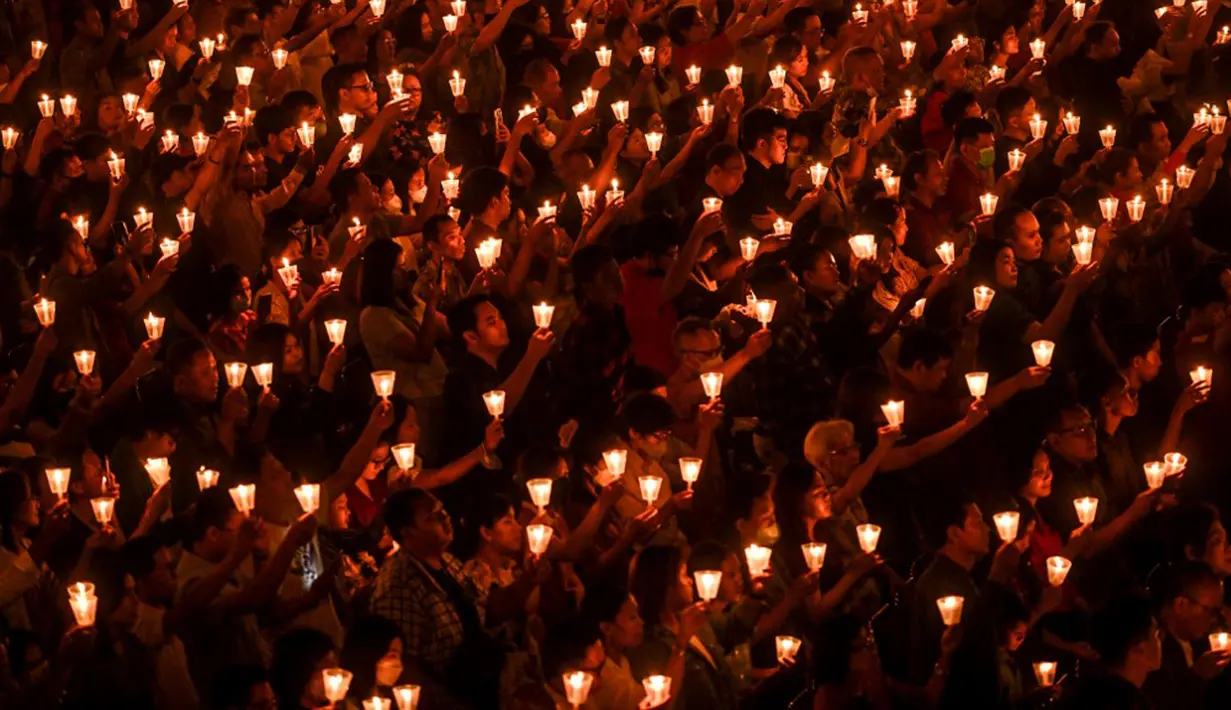 Umat Kristen memegang lilin saat ibadah malam Natal di Gereja Bethany, Surabaya, Jawa Timur, Minggu (24/12/2023). Pelaksanaan ibadah malam Natal berjalan aman dan lancar. (Juni KRISWANTO/AFP)