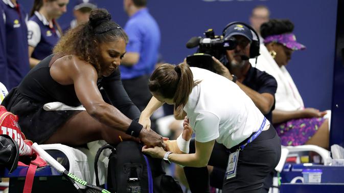 Seorang trainer memeriksa pergelangan kaki Serena Williams saat bertanding menghadapi kakanya, Venus Williams di putaran ketiga turnamen tenis AS Terbuka di New York, Jumat (31/8). Serena mengalahkan Venus dengan skor 6-1, 6-2. (AP Photo/Julio Cortez)