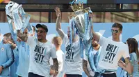 Pemain Manchester City, Kyle Walker, Kevin De Bruyne dan John Stones mengangkat trofi saat melakukan parade juara Premier League di Manchester, Senin (14/5/2018). The Citizens menjadi tim terbaik dengan raihan 100 poin. (AFP/Paul Ellis)