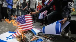 Massa membakar bendera Amerika Serikat dan Israel dalam Aksi Bela Palestina di depan Kedubes AS, Jakarta, Jumat (15/12). Mereka juga mendesak pemerintah Indonesia menghentikan kerja sama diplomatik dengan Amerika Serikat. (Liputan6.com/Faizal Fanani)