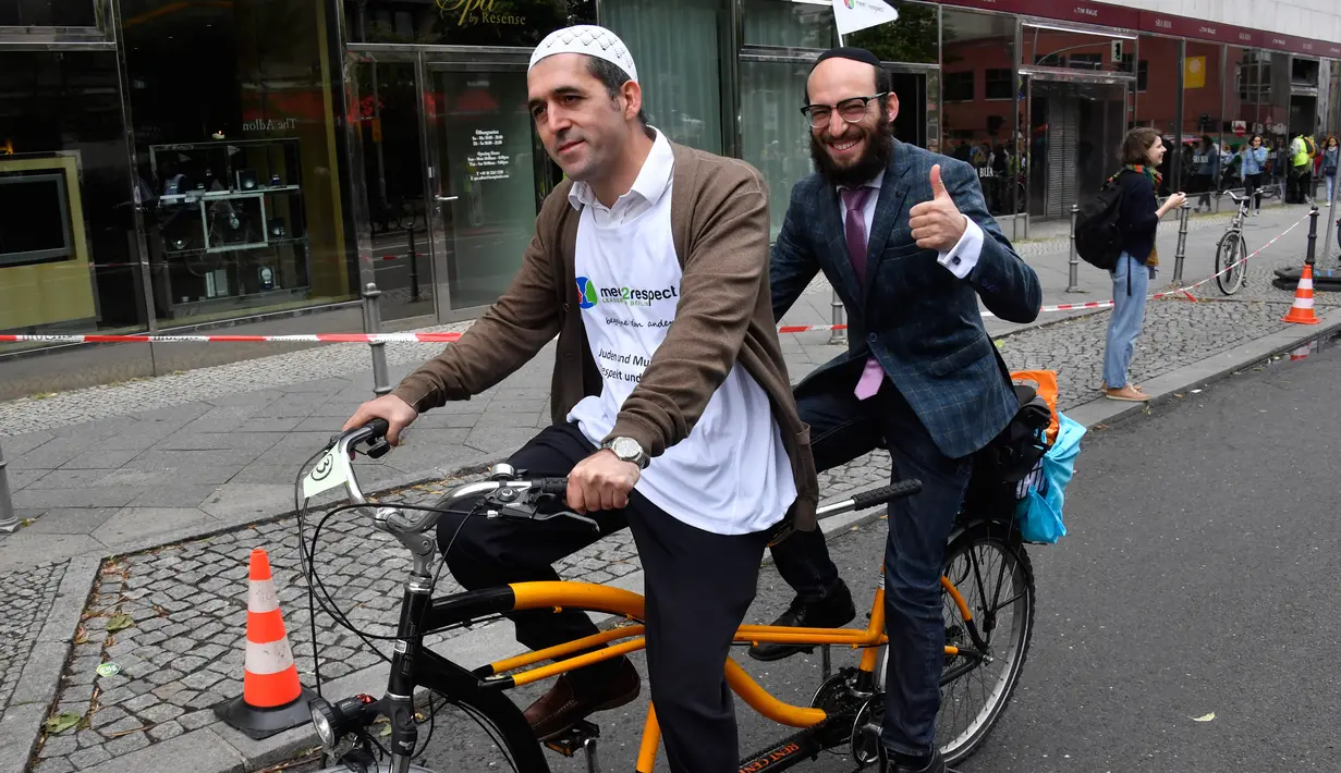 Imam Osman Oers dan Rabbi Akiva Weingarten mengayuh sepeda tandem sebagai kampanye lintas agama melintasi Ibu Kota Jerman, Berlin, 24 Juni 2018. Mereka melakukan aksi damai dengan berkeliling kota Berlin menggunakan sepeda bersama. (AFP/John MACDOUGALL)