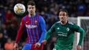 Bek Barcelona, Gerard Pique berebut bola dengan pemain Osasuna, Kike Garcia selama pertandingan lanjutan La Liga Spanyol di di stadion Camp Nou di Barcelona, Senin (14/3/2022). Barcelona menang telak atas Osasuna 4-0. (AFP/Josep Lago)
