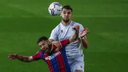 Bek Barcelona, Jordi Alba (kiri) berduel udara dengan striker SD Huesca, Rafa Mir dalam laga lanjutan Liga Spanyol 2020/2021 pekan ke-27 di Camp Nou Stadium, Barcelona, Senin (15/3/2021). Barcelona menang 4-1 atas SD Huesca. (AP/Joan Monfort)