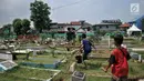 Anak-anak usai membersihkan makam di TPU Cipinang Baru, Jakarta, Minggu (5/5/2019).  Anak-anak yang mayoritas masih duduk di sekolah dasar ini biasanya melayani jasa Ngoret secara berkelompok dengan tugas masing-masing seperti menyapu dan membersihkan sekitar makam. (merdeka.com/Iqbal S. Nugroho)