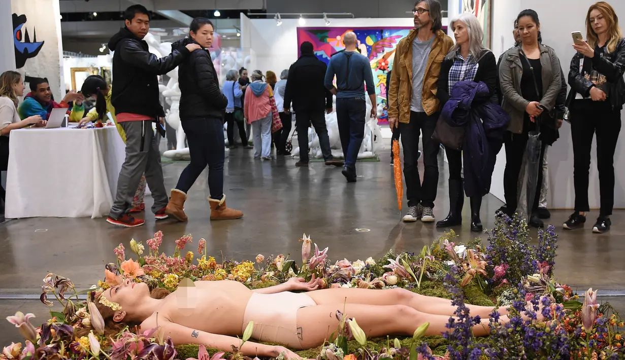 Sejumlah pengunjung mengamati Millie Brown yang terlentang di atas karya seninya saat pameran berjudul 'Wilting Point' atau Titik Layu di LA Art Show, Los Angeles, Minggu (31/1). Brown akan bertahan selama 5 hari hanya meminum air. (Mark Ralston/AFP)