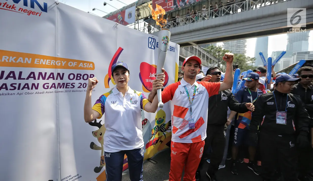 Aktor Reza Rahardian membawa obor secara estafet dan menyerahkan kepada Direktur konsumer Bank BRI Handayani saat prosesi Torch Relay Asian Games 2018 di Jakarta, Sabtu (18/8). Kirab Obor Asian Games telah mencapai puncaknya. (Liputan6.com/Faizal Fanani)