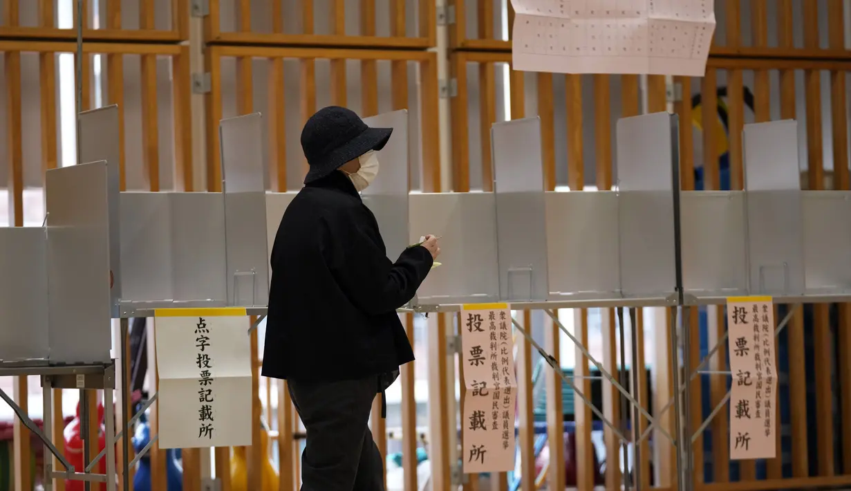 Seorang pemilih bersiap untuk memberikan suaranya dalam pemilihan majelis rendah saat perwakilan dari komisi administrasi pemilihan lokal mengamati di sebuah TPS, Tokyo, Jepang, Minggu (31/10/2021). Jepang menggelar Pemilu di tengah pandemi COVID-19. (AP Photo/Eugene Hoshiko)
