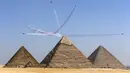 Pesawat KAI T-50 Golden Eagle dari 53rd Air Demonstration Group "Black Eagles" tim aerobatik Angkatan Udara Korea Selatan tampil selama Pyramids Air Show 2022 di atas (kanan ke kiri) Great Pyramid of Khufu, Pyramid of Khafre, dan Pyramid Menkaure di Giza Pyramids Necropolis, Mesir, 3 Agustus 2022. (Mahmoud Khaled/AFP)