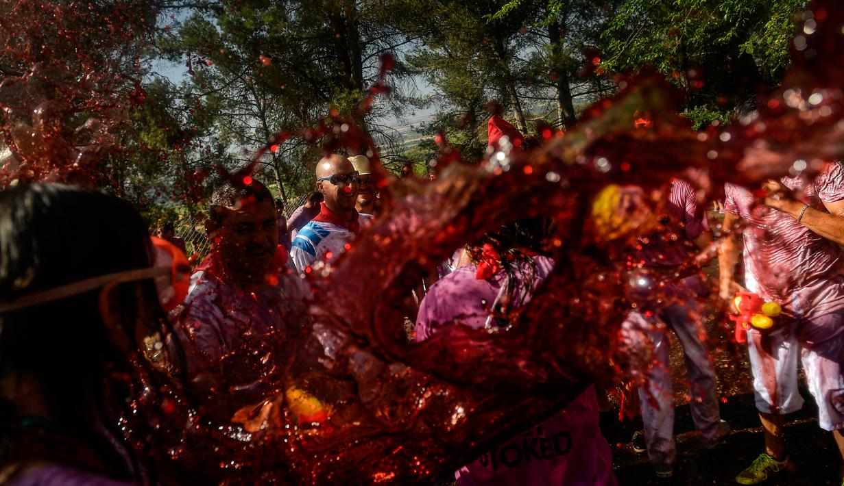 Peserta diguyur anggur merah saat ambil bagian dalam perang anggur di Haro, Spanyol utara, Sabtu (29/6/2019). Ratusan orang berpartisipasi dalam pertempuran musim panas yang terkenal ini dengan menumpahkan ribuan liter anggur merah atau wine ke tubuh peserta satu sama lain. (AP/Alvaro Barrientos)