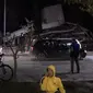 Seorang pria berbicara di ponsel ketika yang lain melihat kerusakan bangunan setelah gempa bumi di Durres,  Albania barat, Selasa (26/11/2019). Gempa bumi bermagnitudo 6,4 mengguncang Albania, Selasa dini hari yang menyebabkan beberapa bangunan dan gedung permukiman runtuh. (AP Photo)