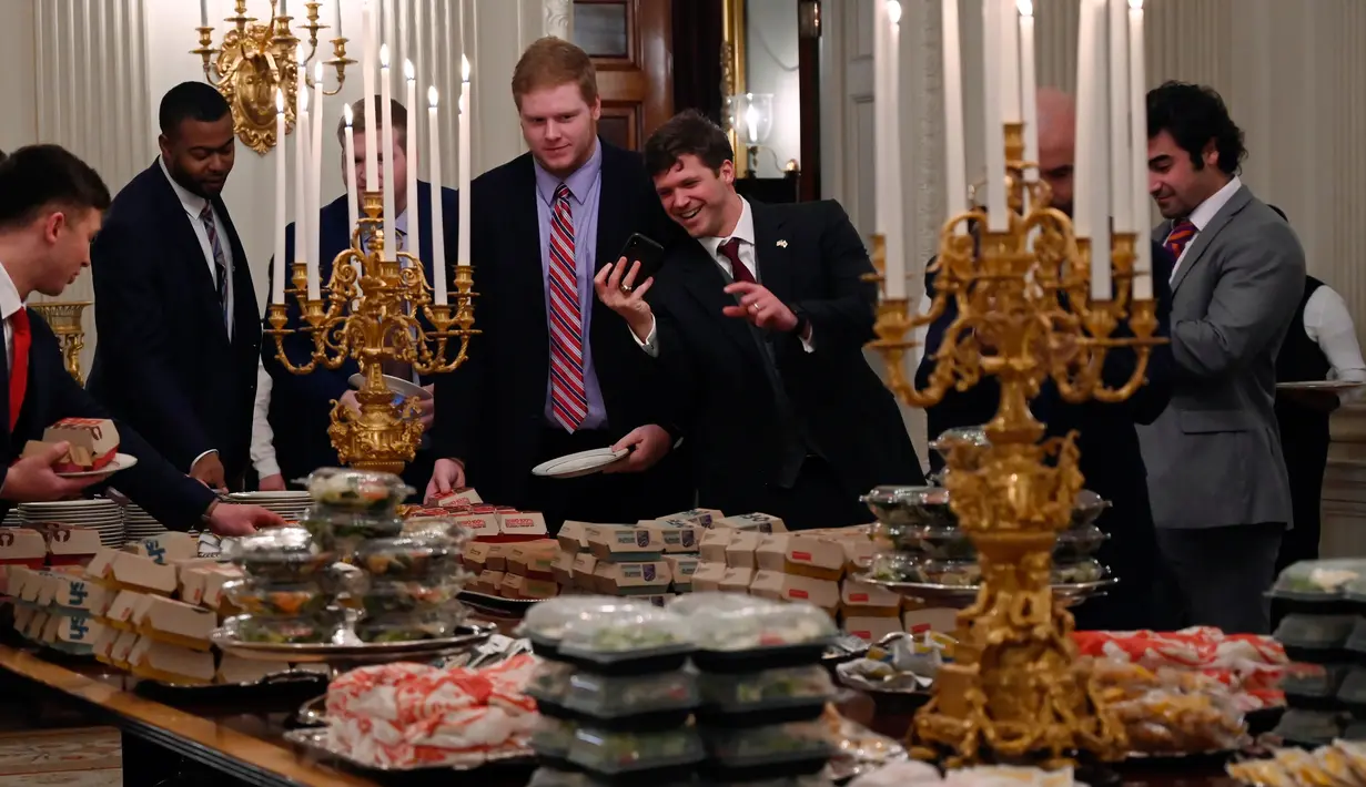 Para pemain Clemson Tigers mengambil makanan cepat saji di Gedung Putih, Washington, Senin (14 /1). Presiden AS Donald Trump menjamu tamunya dengan makanan cepat saji dari McDonald, Wendy, Burger King, Arby dan Domino. (AP Photo/Susan Walsh)