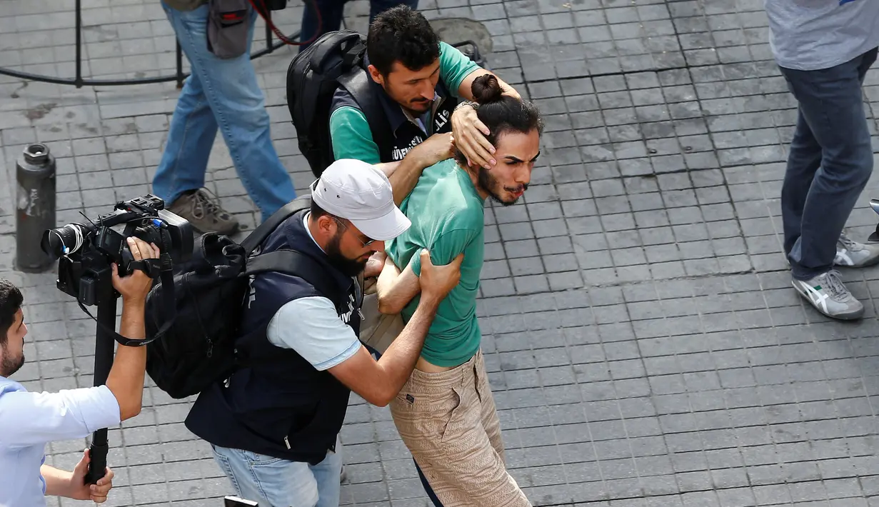 Awak media mengambil gambar aksi polisi berpakaian preman yang menahan aktivis LGBT ketika mencoba melancarkan pawai tahunan, di Istanbul, Minggu (26/6). Pemerintah Turki telah mengeluarkan larangan menggelar pawai tahunan LGBTI. (REUTERS/Osman Orsal)