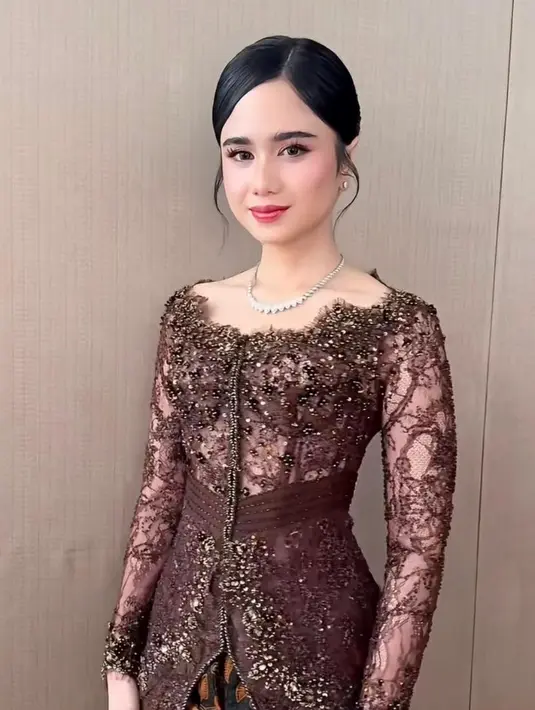 Dari sisi beauty look, riasan wajah karya Nooi Beauty tampil flawless dengan sentuhan soft glam, kulit tampak glowing, blush on peachy yang segar, serta lipstik nude pink yang mempermanis keseluruhan tampilan. Tata rambut dari Sun Hairstylist disanggul rapi dengan belahan tengah, memberikan kesan klasik yang timeless.