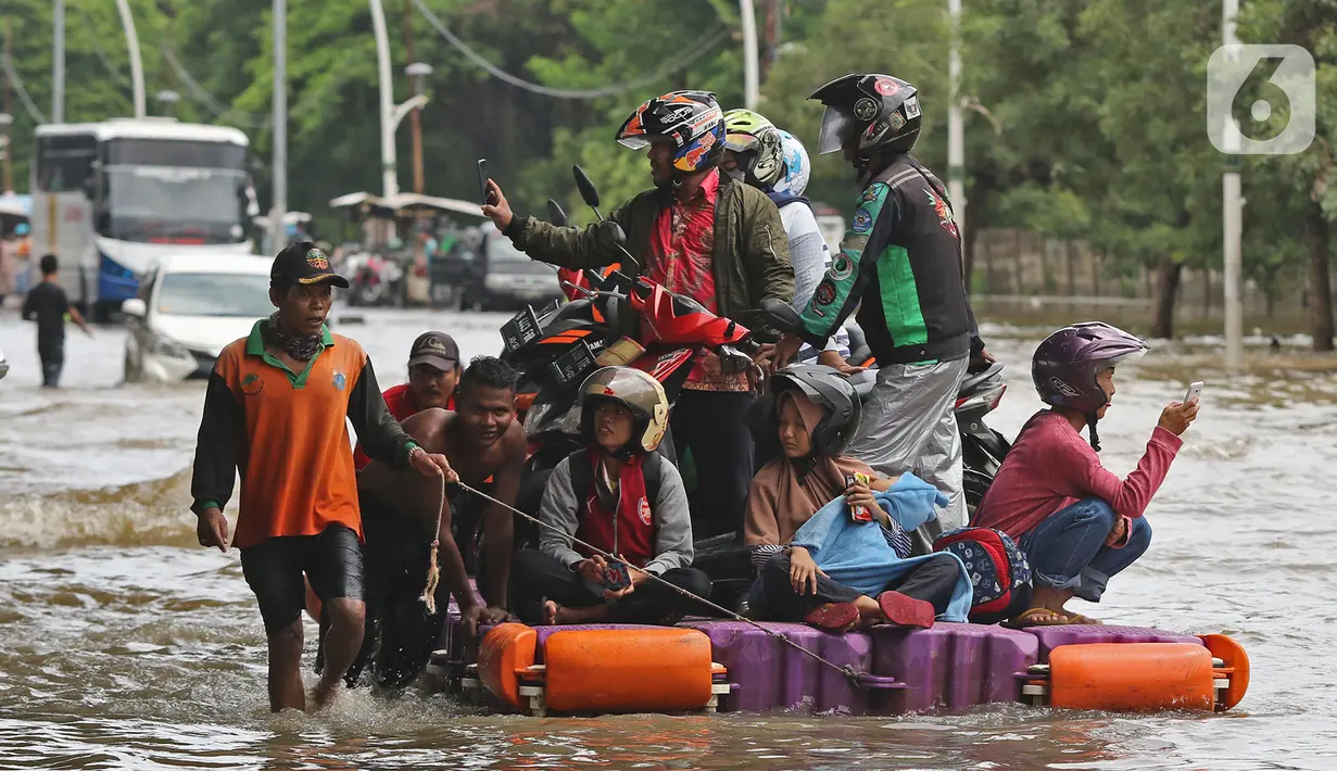 Pengendara sepeda motor menggunakan jasa rakit saat banjir melanda Jalan Ahmad Yani, Cempaka Putih, Jakarta, Minggu (23/2/2020). Banjir yang terjadi dari dini hari tadi melumpuhkan akses jalan tersebut. (Liputan6.com/Herman Zakharia)