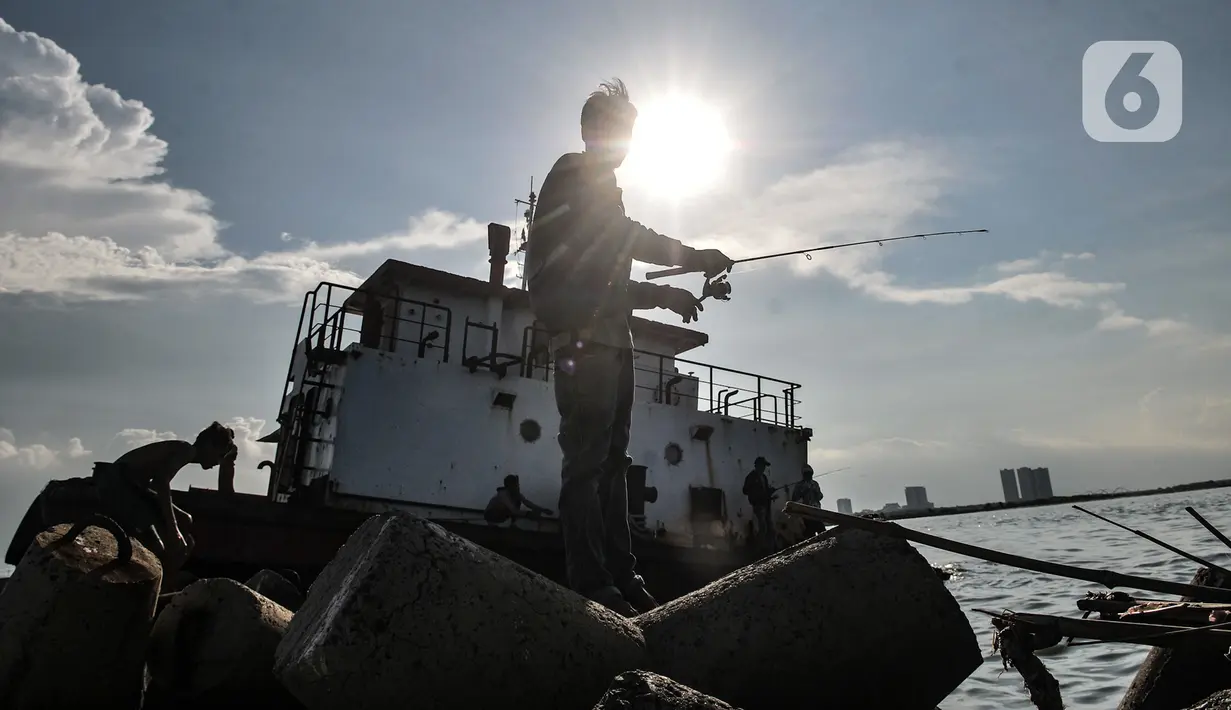Warga memancing di atas sebuah kapal karam di pesisir Kali Adem, Muara Angke, Jakarta, Minggu (27/12/2020). Sebuah kapal yang telah karam selama bertahun-tahun tersebut dimanfaatkan oleh warga sebagai tempat memancing meskipun berisiko membahayakan keselamatan. (merdeka.com/Iqbal Nugroho)