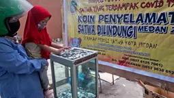 Seorang anak memberikan uang koin ke dalam kotak sumbangan untuk binatang di Kebun Binatang Medan yang terkena dampak virus corona di Sumatera Utara pada 2 Mei 2020. Sudah lebih dari sebulan sejak kebun binatang ditutup sebagai upaya untuk menghentikan penyebaran Covid-19. (AP/Binsar Bakkara)