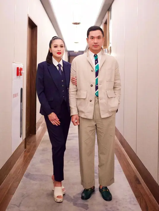 Gaya gemas nan serasi dari pasangan Sandra Dewi dan Harvey Moeis. Sandra Dewi mengenakan setelan jas dan celana panjang, yang dipadu vest dan dasinya berwarna biru navy, dipadukan dengan kemeja putih. Sedangkan Harvey tampil dengan kemeja putih, dasi bernuansa hijau, ditumpuk dengan jaket berkantong dan celana panjang beige yang serasi. [Foto: Instagram/sandradewi88]