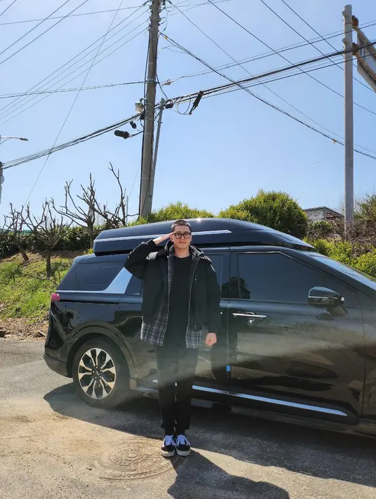 Kim Min Kyu memperlihatkan foto dengan gestur hormat. Dia berdiri tegak di samping van-nya yang berwarna hitam. (foto: Instagram/ mingue.k)