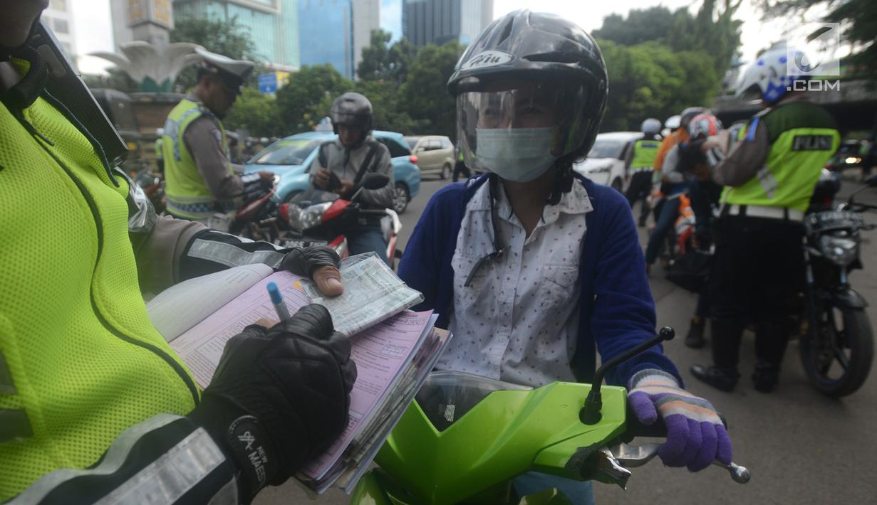 Polantas membuat surat tilang untuk pengendara motor ketika berlangsungnya Operasi Patuh Jaya 2018 di ruas Jalan DI Panjaitan, Jakarta Timur, Jumat (27/4). Razia ini berlangsung selama 14 hari, dari 26 April sampai 5 Mei 2018. (Merdeka.com/Imam Buhori)