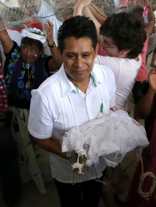 Wali Kota San Pedro Huamelula, Joel Vasque tampak menggendong sang mempelai wanita, yaitu seekor buaya saat akan menjalani ritual pernikahan di Oaxaca, Meksiko, 30 Juni 2015. (AFP PHOTO/MARIO JIMENEZ) 