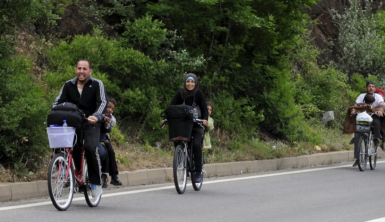 Sebuah keluarga imigran Suriah menaiki sepeda bersama di dekat perbatasan Yunani di Makedonia, Rabu (17/6/2015). Mereka mencari perlindungan dengan menempuh ribuan kilometer. (REUTERS/Ognen Teofilovski)