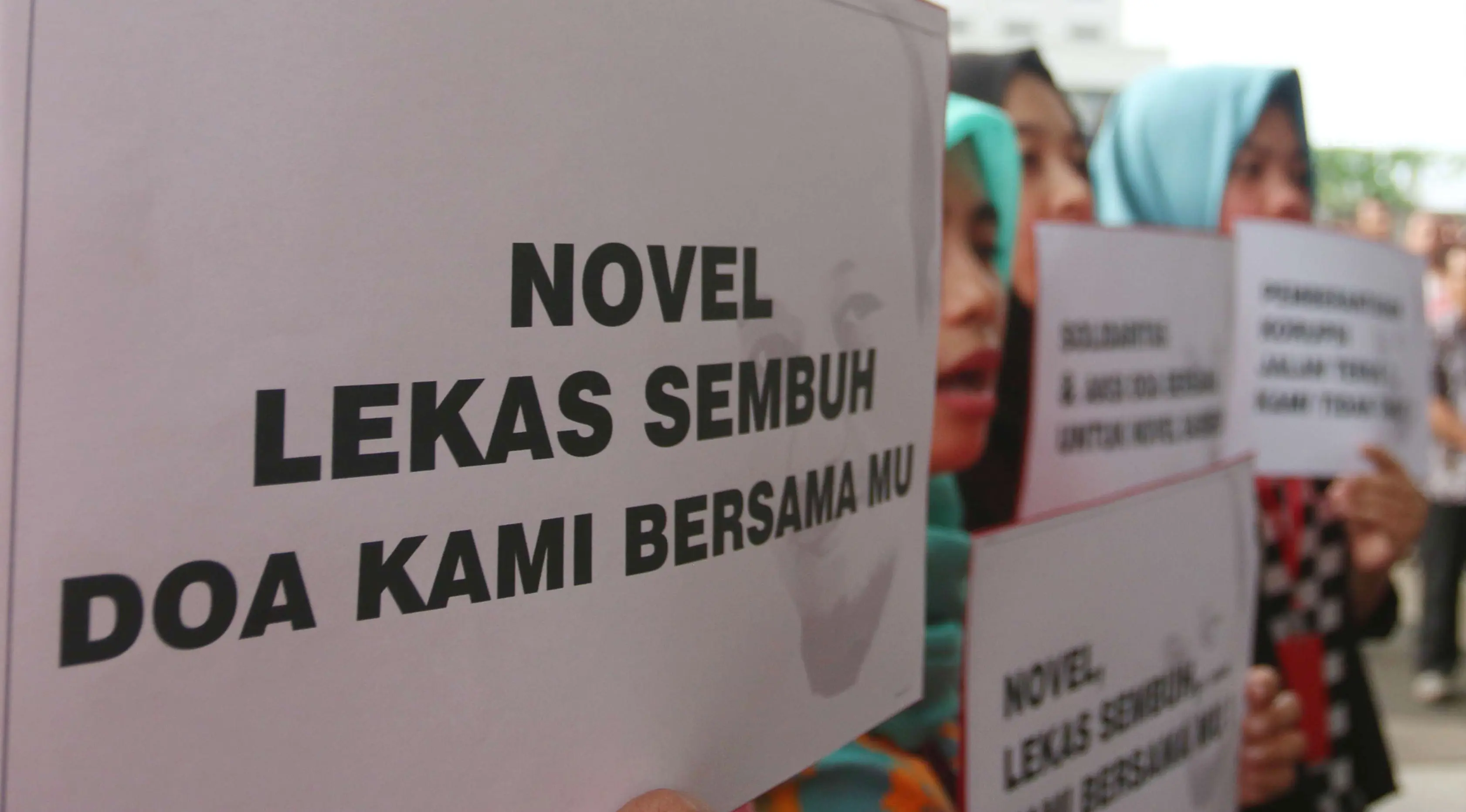 Sejumlah orang membawa poster ungkapan kepedulian saat mengikuti aksi peringatan 100 hari penyerangan Novel Baswedan di gedung KPK, Jakarta, Kamis (20/7). (Liputan6.com/Helmi Afandi)