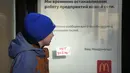 Seorang anak melewati tanda 'No War!' yang menempel di jendela restoran McDonald's dengan pemberitahuan penutupan restoran di St. Petersburg, Rusia, Selasa (15/3/2022). Gerai makanan siap saji McDonald's resmi menutup 850 gerainya yang beroperasi di Rusia pada 14 Maret 2022. (AP Photo)