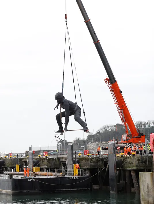 Patung perunggu terbesar di Inggris,  berjudul 'Messenger' tiba dengan tongkang di pesisir pantai Plymouth, Senin (18/3). Patung itu mengambarkan seorang wanita dengan tinggi 7m dan lebar 9m dalam posisi berjongkok. (REUTERS/Peter Nicholls)