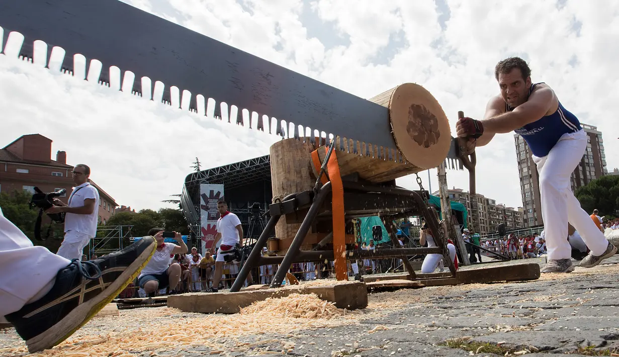 Peserta menggergaji batang pohon dengan "tronza", gergaji tradisional daerah Basque, pada hari ketiga festival San Fermin di Pamplona, Spanyol, Senin (8/7/2019). Festival San Fermin menghadirkan beberapa olahraga pedesaan Basque seperti menggergaji dan memotong pohon dengan kapak. (JAIME REINA/AFP)