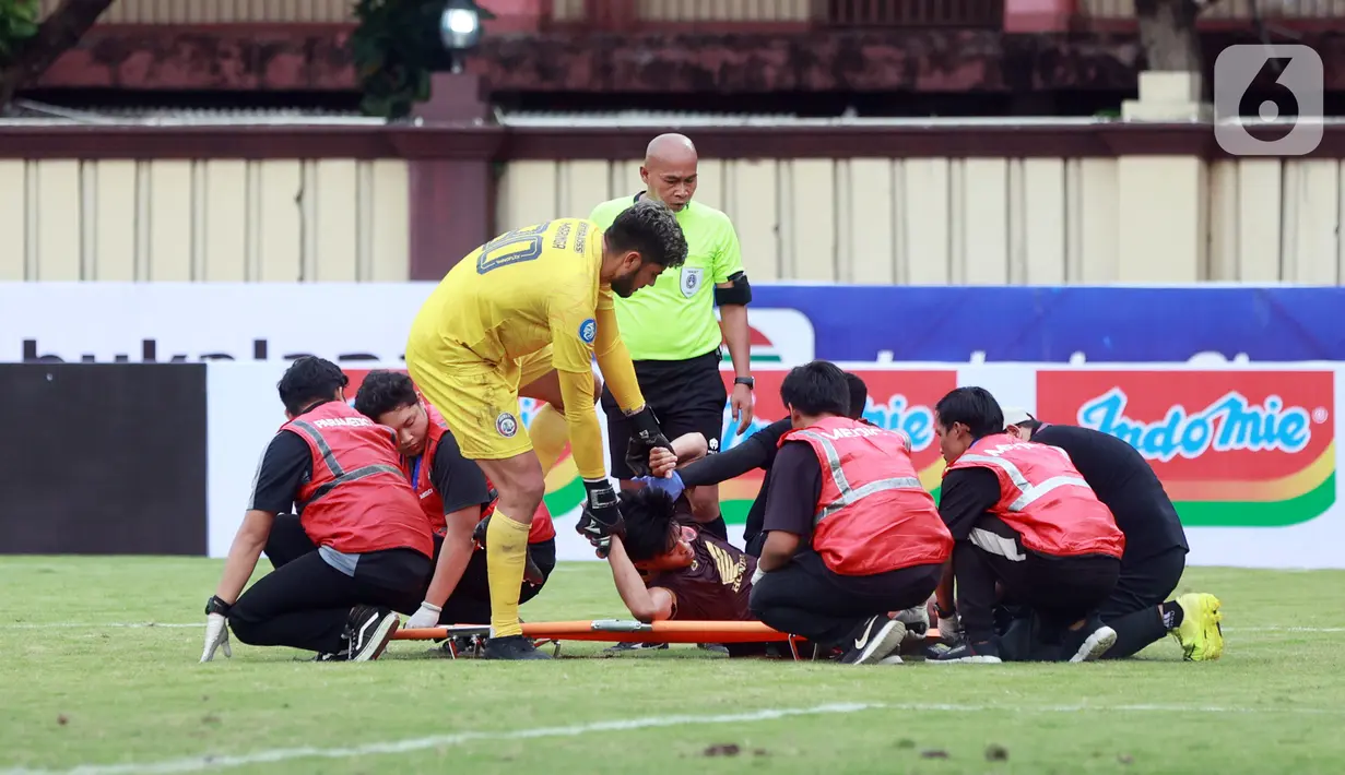 Kiper Arema FC, Adilson Maringa, membantu mengangkat pemain PSM Makassar ke tandu pada laga BRI Liga 1 di Stadion PTIK, Jakarta, Sabtu (4/2/2023). PSM Makassar menang dengan skor 1-0. (Bola.com/M Iqbal Ichsan)
