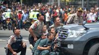 Sejumlah polisi mengambil posisi di dekat sebuah mobil saat melakukan pengejaran terhadap pelaku ledakan di pospol Sarinah, Jakarta, Kamis (14/1). Baku tembak terjadi di depan Sarinah setelah suara ledakan ketiga terjadi.  (AFP PHOTO/Bay Ismoyo)