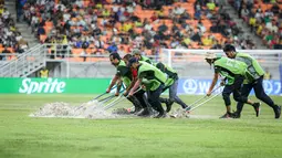 Sejumlah petugas menyingkirkan air yang menggenangi lapangan Jakarta International Stadium (JIS) jelang laga perempat final Piala Dunia U-17 2023 antara Timnas Brasil U-17 melawan Timnas Argentina U-17, Jumat (24/11/2023). (Bola.com/Bagaskara Lazuardi)