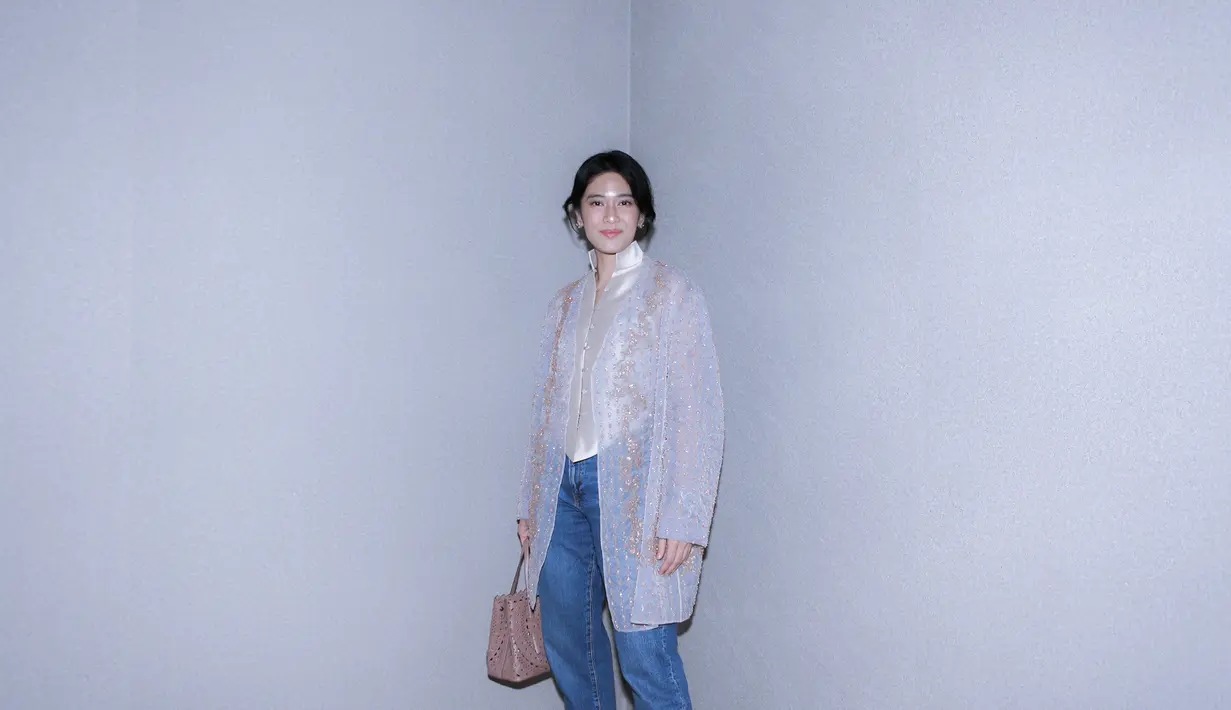 Dian Sastro tampil tak kalah memesona. Ia memadukan inner dengan aksen cheongsam bernuansa keemasan, dipadu outer transparan berbordir emas, dan celana jeans. [Foto: Document/FIMELA]