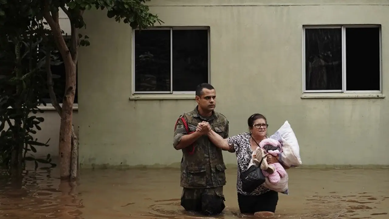 Seorang tentara membantu seorang wanita mengungsi dari lingkungan yang terendam hujan lebat di Canoas, Negara Bagian Rio Grande do Sul, Brasil, Sabtu (4/5/2024).