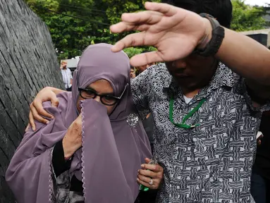 Istri Hakim MK Patrialis Akbar, Sufriyeni (kiri) menutup wajah saat menuju ruang tahanan KPK, Jakarta, Senin (30/1). Patrialis Akbar menjadi tersangka dugaan penerima suap uji materi UU peternakan dan Kesehatan Hewan. (Liputan6.com/Helmi Fithriansyah)