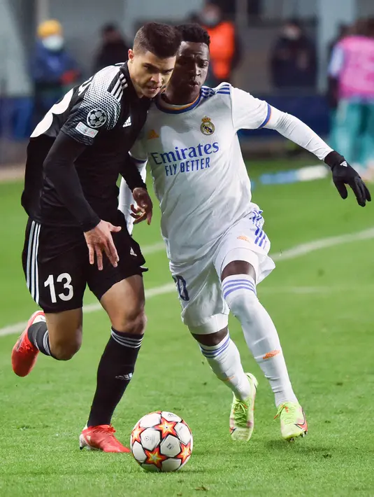 Bek Sheriff Tiraspol Fernando Costanza Peixoto dan penyerang Real Madrid Vinicius Junior bersaing  dalam laga matchday 5 fase grup Liga Champions 2021/22 di Bolshaya Sportivnaya Arena, Kamis (25/11/2021) dini hari WIB. Real Madrid sukses menghajar Sheriff Tiraspol dengan skor 3-0. (Sergei GAPON/AFP)