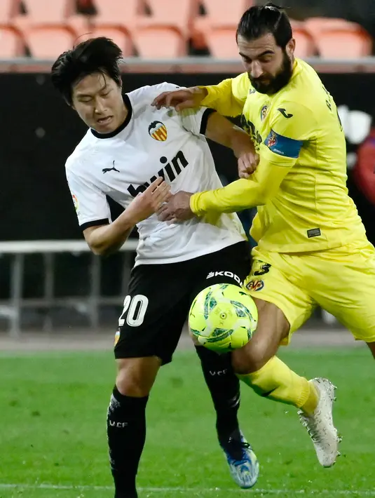 Gelandang Valencia, Kangin Lee berebut bola dengan bek Villarreal, Raul Albiol pada pertandingan lanjutan La Liga Spanyol di stadion Mestalla di Valencia (6/3/2021). Pulang tanpa poin membuat pasukan Unai Emery masih tertahan di peringkat ketujuh dengan koleksi 37 poin. (AFP/Jose Jordan)