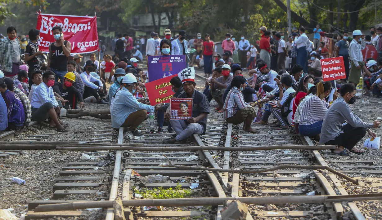 Demonstran duduk di rel kereta api setelah memblokir rel kereta api selama protes terhadap kudeta militer di Mandalay, Myanmar (17/2/2021). Aksi protes tersebut menghentikan layanan kereta api antara Yangon dan kota selatan Mawlamyine. (AP Photo)