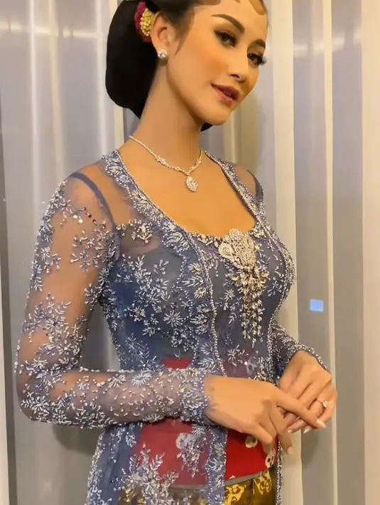 Kebaya nuansa warna ungu itu dipadukan dengan stagen merah dan kain batik warna coklat. [@anarav.label].