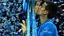 Novak Djokovic mencium trofi juara turnamen tenis ATP World Tour Finals di London, Inggris, (22/11/2015). (AFP Photo/Glyn Kirk)